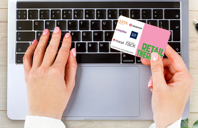holding retail therapy gift card on computer